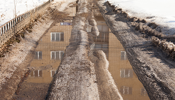 Lumisella kadulla ajourien vesi heijastaa kerrostalon julkisivun. Kuva: Stanislaw Mikulski, AdobeStock.